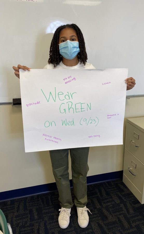 Tori Fergus ‘22 holds up a poster reminding students to participate in raising awareness about mental health.